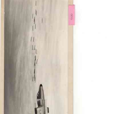 wide Angle shot of CF-100 #18101 firing rockets ; photo mounted on stiff cardboard. Writing on reverse 18101 Feb 7, 1953 or later P. Cope