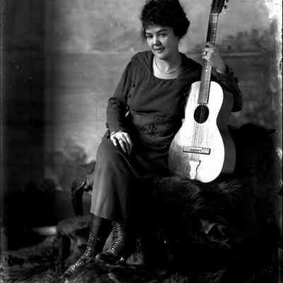 Unidentified female, seated, holding a guitar, glass-plate negative