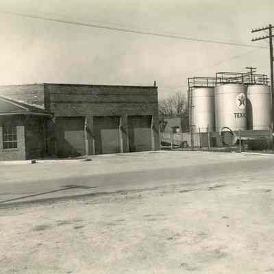 Automotive gasoline station/building with Texaco gasoline storage tanks behind it.