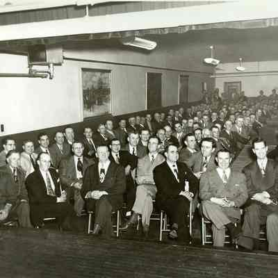 Group business men, seated, in a large room
