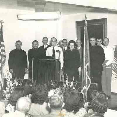 Male speaker, unidentified, at a podium speaking to a group of seated persons
