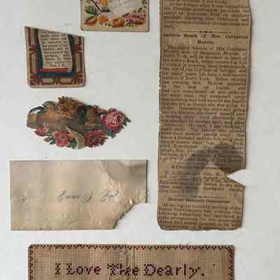 Ephemera tipped into the bible. Including an embroidered bookmark, a newspaper article, calling card, and three funerary cards.