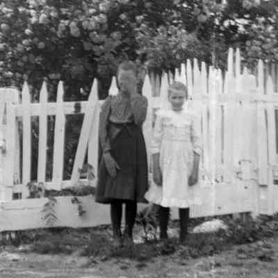 2 girls in front of picket fence