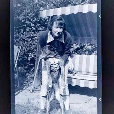 Negative of Emma Cohen Bray holding a dog upright