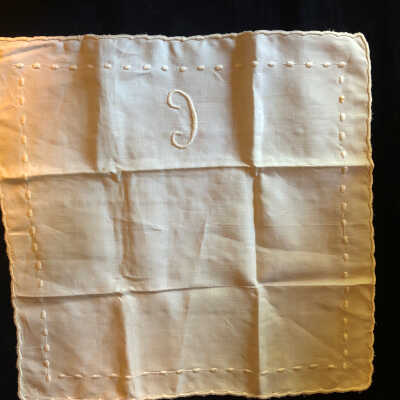 Embroidered dot table linen with letter “c” on one side and scalloped edges