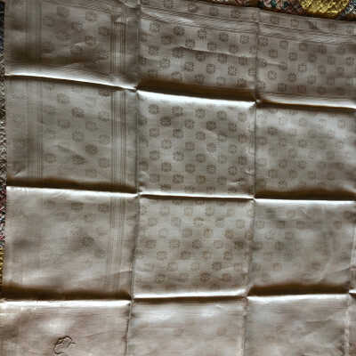Jacquard table cover with windowpane border design and flowers all over, “C” monogram on one corner