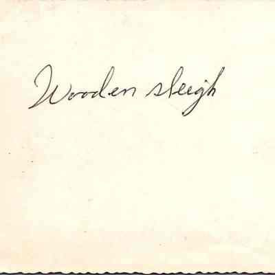 Wooden Sleigh written on the back of the photograph with the young man in the horse-drawn sleigh.: The image shows the words "Wooden Sleigh" handwritten in elegant script on the back of the picture.