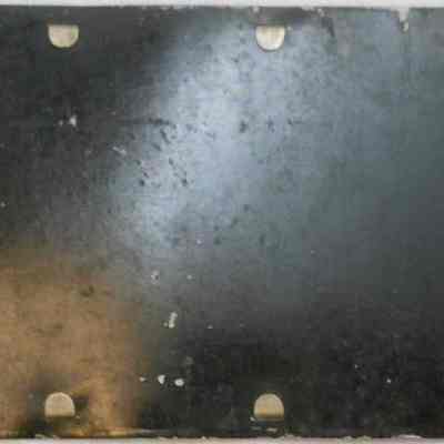 NJ License Plate for R.Y. Durland's 1915 Oldsmobile "Four" Model 43 verso: The image shows the reverse disc off the old, weathered license plate with the numbers 28451 and letters NJ.