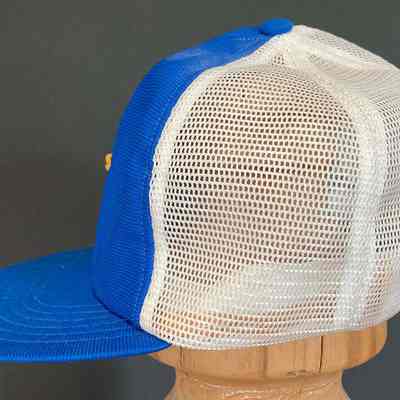 Stephen Schlinger's Troy Little League Team cap - left side: The image shows a blue and white mesh trucker cap displayed on a wooden stand.