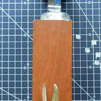 Charter Member Leander Keeney Trophy right side: The image shows a vintage trophy on a grid mat, featuring a wooden base and metal helmet.