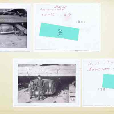 The image shows two black-and-white photographs on a yellowed background, each depicting the aftermath of Hurricane Hazel in 1954. The upper left photo captures a car partially buried under a collapsed wooden structure, with handwritten red text saying "Hurricane Hazel" and the date "10-15-54" next to it. The bottom right photo features two boys standing next to another partially buried car, also affected by the hurricane, with similar handwriting above. Both images reflect the significant damage and destruction caused by the storm. Green rectangular stickers with numbers are on each photograph.