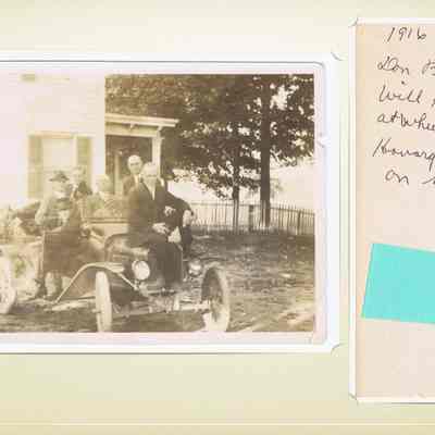 Don Barrell sitting in door Will, Percy, John at wheel, Earnest and Howard - Baird sitting on hood.: The image shows a vintage photograph from 1916 depicting a group of men gathered around an old-fashioned car in a rural setting. Two men are seated in the car, while another is outside, casually leaning on the vehicle. A handwritten note on the side lists names associated with the people in the photo. The scene is set against the backdrop of an old house with shutters, a porch, and a white picket fence. The men are dressed in formal attire typical of the early 20th century, providing a glimpse into the fashion and automotive culture of the time.
