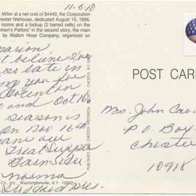 Address side of the " Fire Engine House in Chester, N. Y." postcard.: The image shows the back of a postcard with handwritten cursive text expressing personal sentiments. It features a heart-shaped American flag sticker and is addressed to "Mrs. John Cavallero" in Chester, NY. The printed text mentions it's published by the Chester Historical Society and provides a brief history of a firehouse built in Chester on August 10, 1896, organized by the Walton Hose Company.