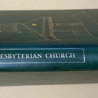 Spine: The image depicts a large, hardcover book with a dark green spine, titled "Chester Presbyterian Church" in white capital letters. The spine, which is textured, features a simple decorative outline of a steeple and is bound tightly to ensure durability. The background is a neutral beige, allowing the book's deep green to prominently stand out. Additionally, there are initials "LRA" printed at the bottom of the spine, providing an indication of the book’s possible classification or ownership. The overall presentation of the book gives it a formal and authoritative appearance, suggesting it might contain significant historical or religious content pertaining to the Chester Presbyterian Church. The quality of the book's binding further indicates the care taken in its compilation and preservation, suggesting it might be an important resource for its intended audience. The photograph focuses on the spine, with the edges of the book just visible, emphasizing the clarity and prominence of the title and design.