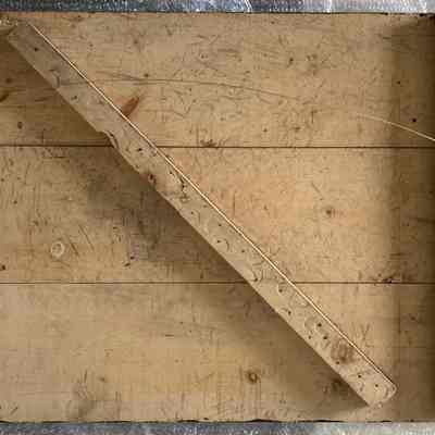 VS 52 - CHS 76 Score Board - reverse.: The image shows a wooden structure with horizontal planks, featuring a diagonal support beam adorned with numerous nails
