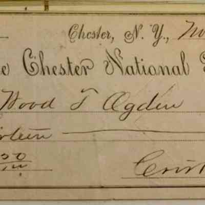 Ogden Side A: The image shows an old check from The Chester National Bank in Chester, New York, dated November 7, 1883. The check is made out to an individual with the name Wood J. Ogden. The amount is specified as thirteen dollars and twenty cents, written out as $13.20. The check features ornate designs on the left side, with decorative loops forming a vertical pattern. The handwriting on the check is elegant and typical of the era, with flourishes that add to its historical charm. The check is intended to be cashed or deposited by the person named, as indicated by the term "or Order." The signature line is signed by someone whose name appears to be Crist & Sow