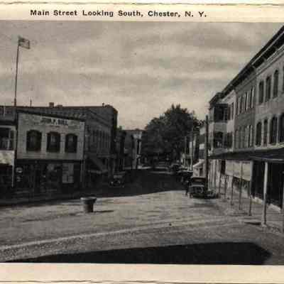 20829 Main Street looking south.: The image shows downtown Main Street in Chester, N.Y., with vintage cars and American flags.