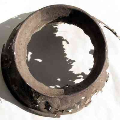 William A. Lawrence & Son milk can remnant - top view: The image shows the rusted top of a milk can with irregular jagged edges and significant deterioration.