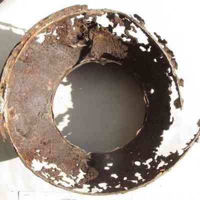 William A. Lawrence & Son milk can remnant - bottom view: The image shows the underside of a heavily rusted, top section of a 40-quart milk can with many holes and rough edges.