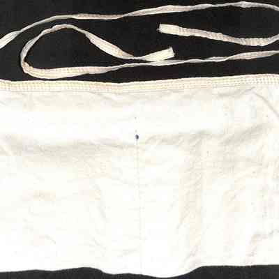 Chester Lumber Apron - reverse.: The image shows a plain white apron with two long straps, laying flat on a dark background.