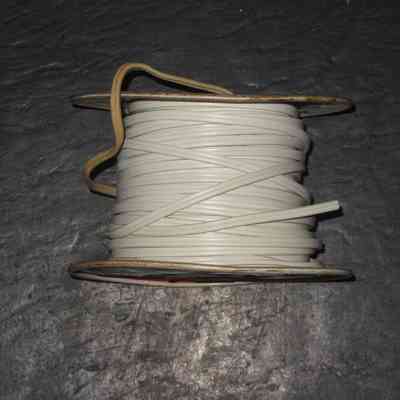 Citco Wire Spool - edge view: A coiled spool of white electrical two-conductor cord is resting on a dark textured surface. The spool of wire is labeled "Cities Service Company."