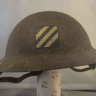 Nick Uyhelyi's WWI Helmet - front view: The image shows a vintage military helmet with a textured surface, featuring the diagonal striped  AEF 3rd Division Insignia on the front.