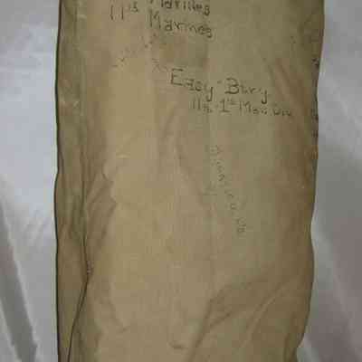 John J. McGrath's Duffel Bag: A khaki military bag with handwritten text standing upright.