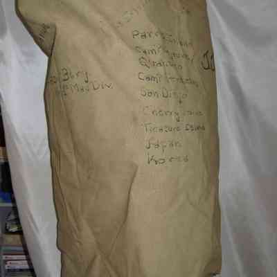 John J. McGrath's Duffel Bag: A khaki bag displays handwritten locations, including Camp Lejeune and San Diego, on its surface.