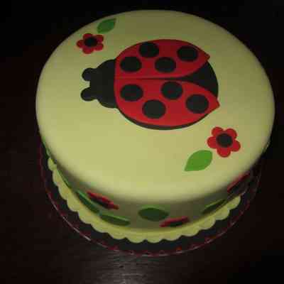 Satin Fine Foods “Ladybug” Fondant example - view 1: The cake features a ladybug design with red flowers and green leaves for decoration.