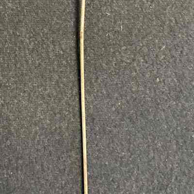 Hat Pin with Cut Green Glass Finial.: The image shows a turn-of-the-century hat pin with a decorative green top against a textured dark background.