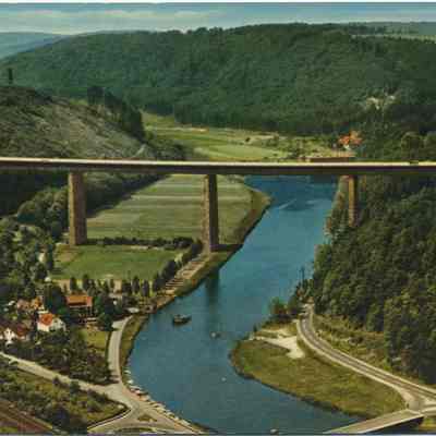 Warratal post card to Chester Lumber: This color photo postcard portrays the majestic Werratal Autobahn bridge spanning over a serene Werra river nestled within a lush, green valley.