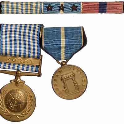 John J. McGrath's Korean War Service Medals - recto: The image depicts two military medals and a ribbon bar. The first medal is the United Nations Service Medal for Korea, featuring a blue and white striped ribbon with the word "KOREA" on a bar, and a gold medallion adorned with the UN emblem. Beside it is the Korean Service Medal, featuring a blue ribbon with a white stripe and a medallion engraved with a structure and the words "KOREAN SERVICE." Above these medals is a ribbon bar with three bronze service stars.