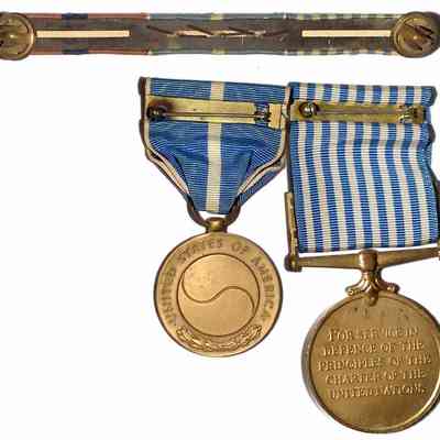 John J. McGrath's Korean War Service Medals - versa: The image shows the back of United States military medals with blue ribbons and accompanying service bars on display.