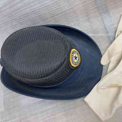 Angie Musumeci's American Legion Cap & Gloves: A navy hat with an "American Legion Auxiliary" patch rests beside white gloves on a textured surface.