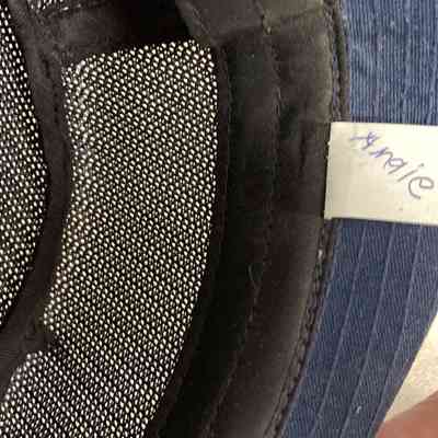 Angie Musumeci's American Legion Cap - tag marked Angie.: A hand holds a yellow paperclip near a note attached inside a cap.