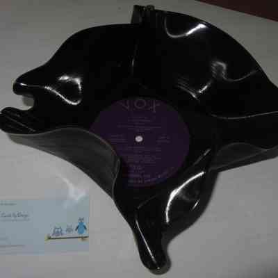Melted Record: The image shows a black vinyl record transformed into a decorative bowl, alongside a small business card.