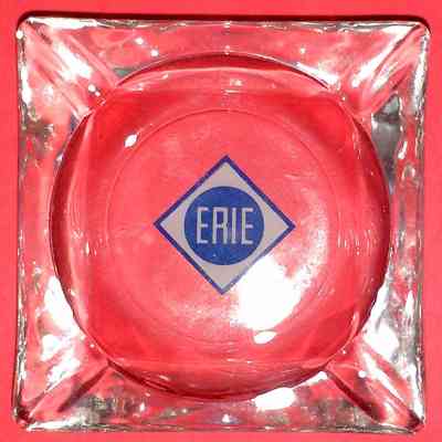 Erie Railroad Square Glass Ashtray - top.: A square, clear glass ashtray sits on a red background with "ERIE" in a central diamond.