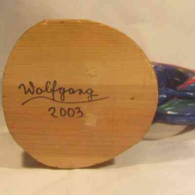Rooster - bottom: A wooden, colorful, painted wooden rooster sculpture with "Wolfgang 2003" written is on the bottom of the stand.