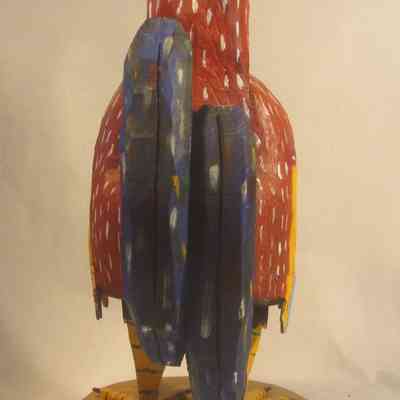 Rooster - back: The image shows a colorful, painted wooden rooster sculpture with vibrant red, blue, and yellow patterns.