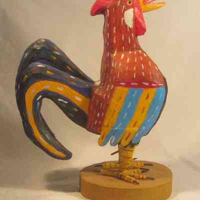Rooster - right side: The image shows a colorful, painted wooden rooster sculpture with vibrant red, blue, and yellow patterns.