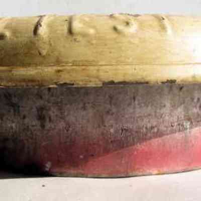 Sheffield Farms milk can lid - side view: The image shows a vintage milk can lid with a round base, red and black coloration, and a light-colored