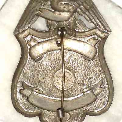 Erie Railroad Watchman Badge - back, pin closed.: The image shows a metallic pin-back badge with eagle design, featuring text and circular markings.