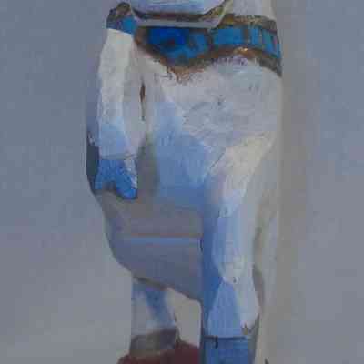 Unicorn - front: A painted wooden unicorn statuette stands on a red base, highlighted with blue accents.