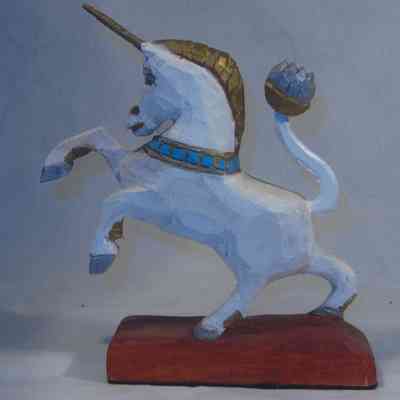 Unicorn - left side: A wooden unicorn, painted white with gold and blue accents, is posed majestically on a wooden base