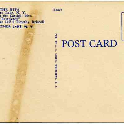 Address side of the "The Rita" postcard.: The image shows the back of a vintage postcard, primarily in a beige color with blue text and a blue square indicating where to place a stamp. The text references "The Rita," located on White Lake and high in the Catskill Mountains, New York, and includes a phone number for Timothy Driscoll. There is also a visible aged stain running down the middle, giving it an authentic old look, and it’s marked Kauneonga Lake, N.Y. at the bottom.