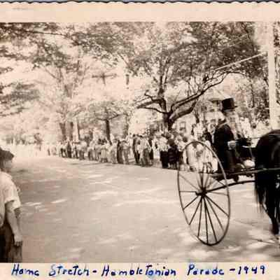 Home Stretch - Hambletonian Parade - 1949: The photo depicts a horse-drawn carriage driven by Bill Conklin and spectators lining the street.