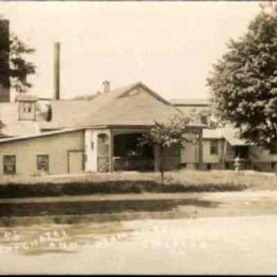 Lawrence’s Neufchatel and Cream Cheese Factory, Chester, N. Y.: This monochrome photo postcard depicts the Lawrence’s Neufchatel and Cream Cheese Factory on the Chester-Goshen road. It is set in a spacious area with trees. Notably, the building features a prominent chimney and several windows, and is labeled "Lawrence’s Neufchatel and Cream Cheese Factory, Chester, N. Y."