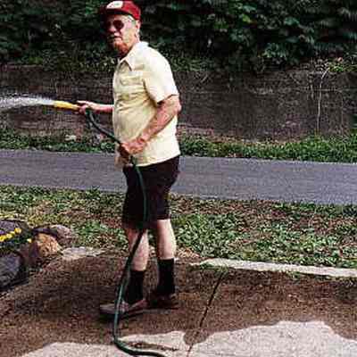 Larry Neeb watering flower bed along trail