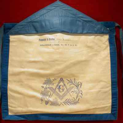 Apron: White lambskin with blue silk backing, trimmed with blue silk. Presented to Brother Mic Adams, Columbus Lodge #75, May 15, 1876. 13 14/" x 15 1/2"