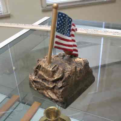 Paperweight: Bronze collored rack with waving American flag. God Bless American engraved on front.